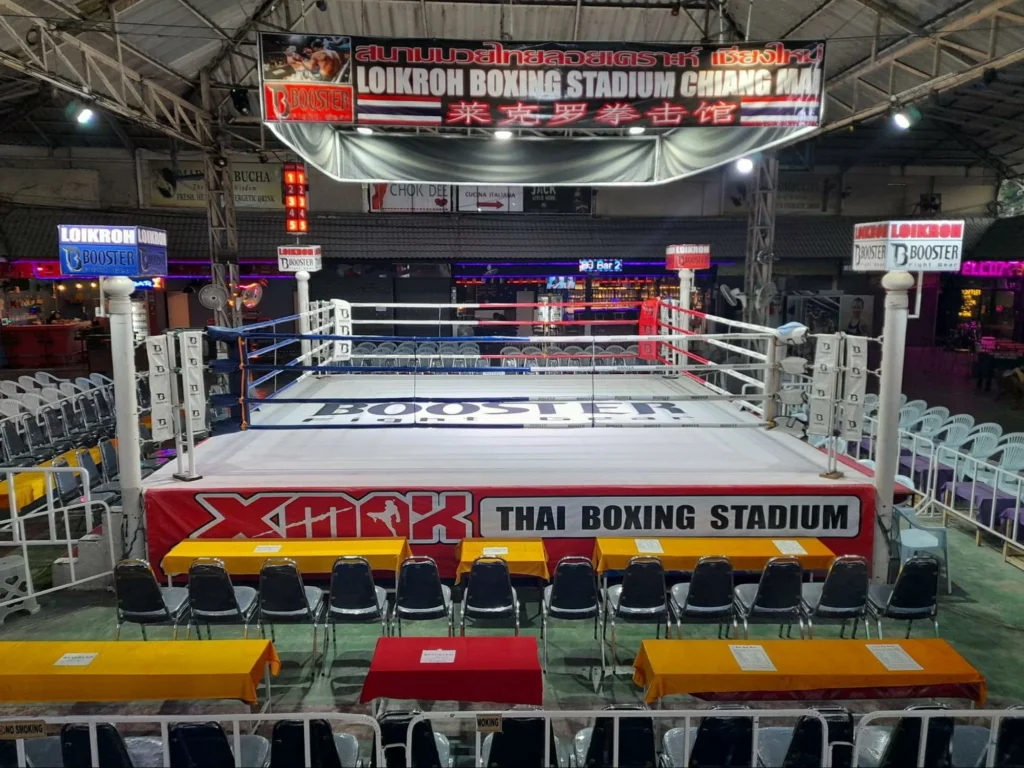 An empty boxing ring at Loi Kroh Boxing Stadium in Chiang Mai, surrounded by chairs and tables with a clean and organized setup before the event starts.