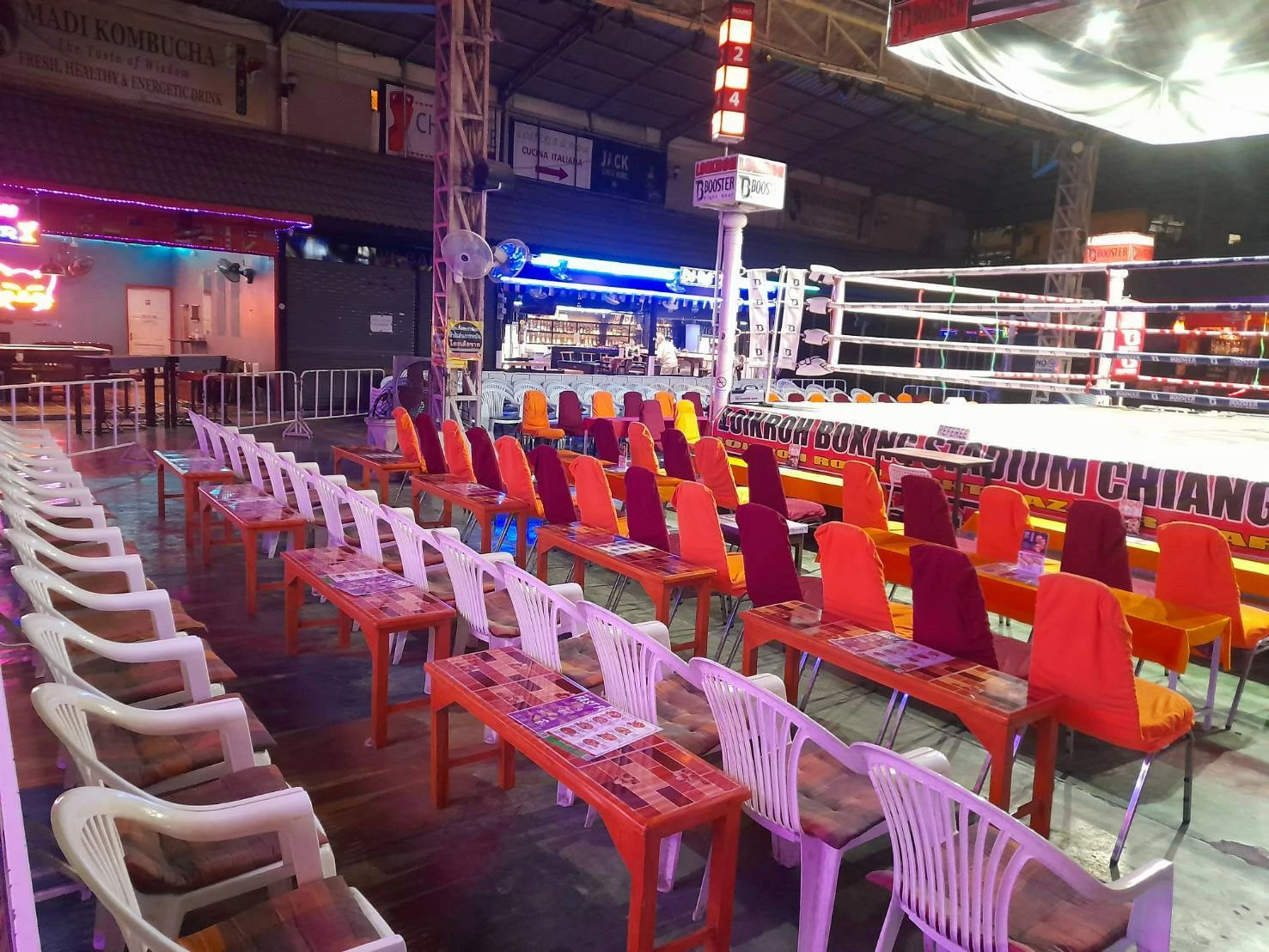 Colorful chairs and tables arranged neatly in front of the boxing ring at Loi Kroh Boxing Stadium, creating an organized setup for the audience.
