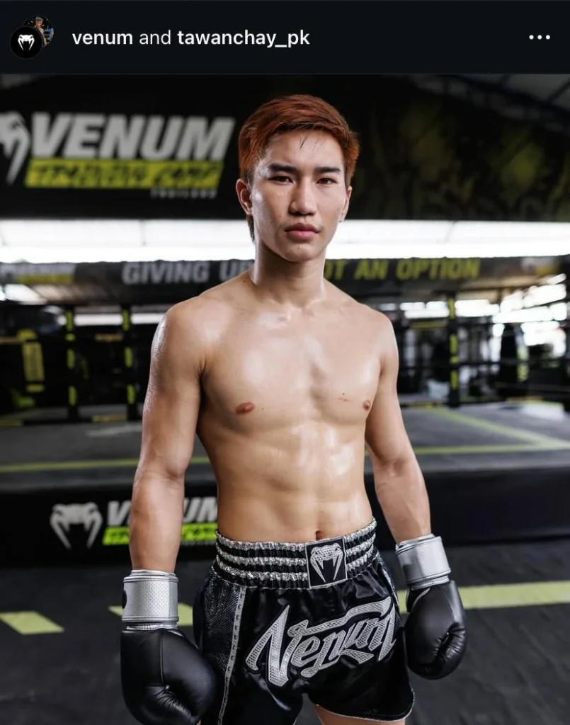 Tawanchai, a professional Muay Thai fighter, standing confidently at Venum Gym in black training gear and gloves.