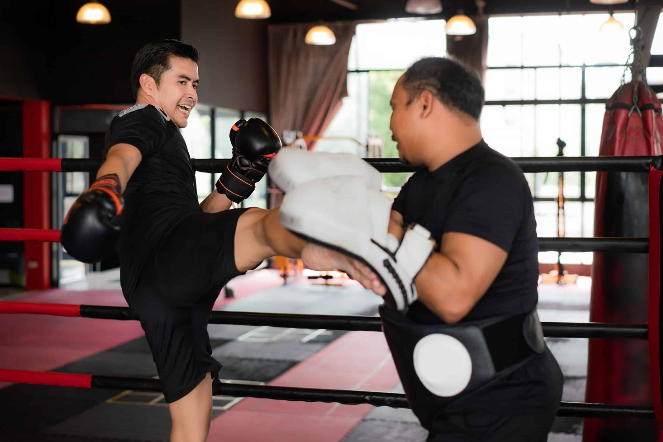 Professional Asian Kick boxer kicking professional trainer in bo