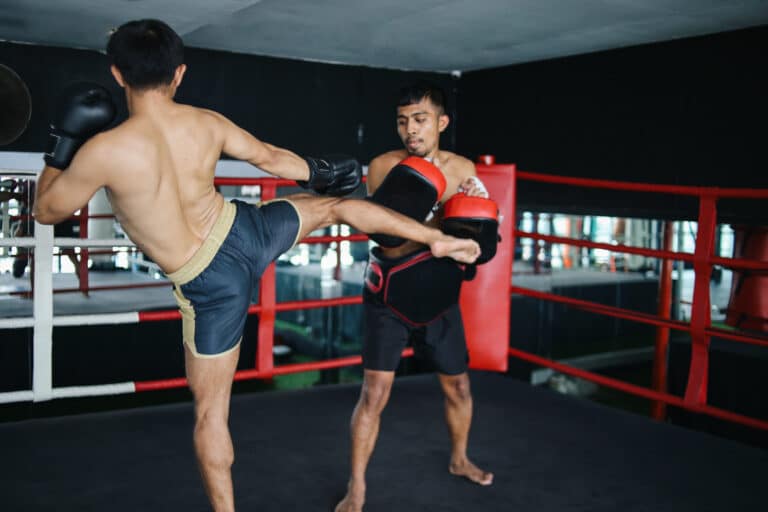 Two Asian Thai boxing man practices fight together with protective equipment boxing ring