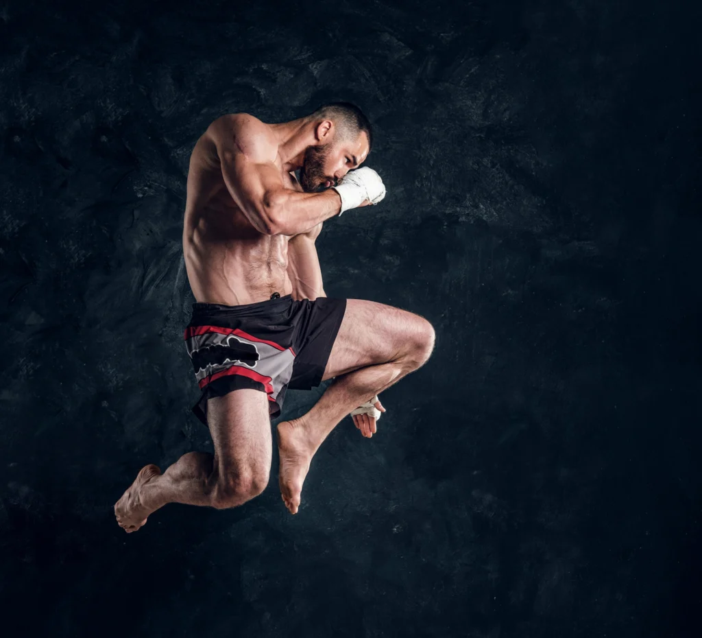 focused physically fit man is jumping making illusion flight before punch dark studio