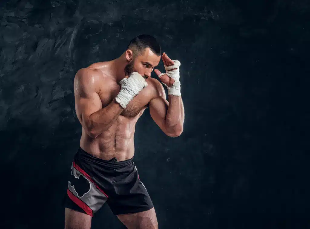 strong muscular fighter is showing his punch while posing photographer dark photo studio ()