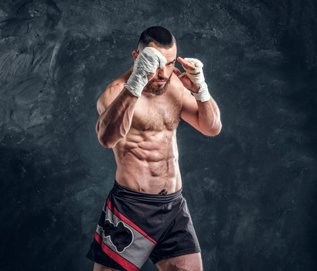 strong muscular fighter is showing his punch while posing photographer dark photo studio